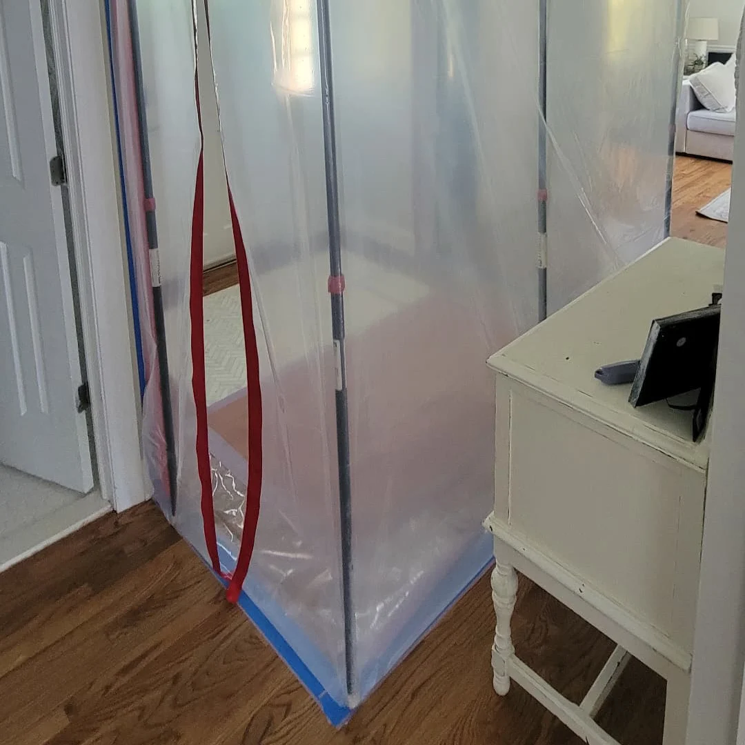 Professional mold containment barrier with zipper door and floor sealing installed to prevent cross-contamination during mold remediation in Monmouth County, New Jersey.